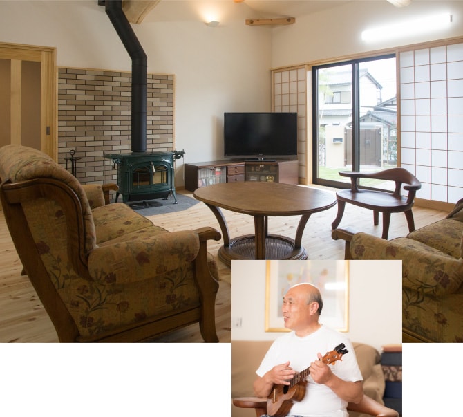 Sさま邸 内観 薪ストーブのある部屋の様子 ギターを弾く男性